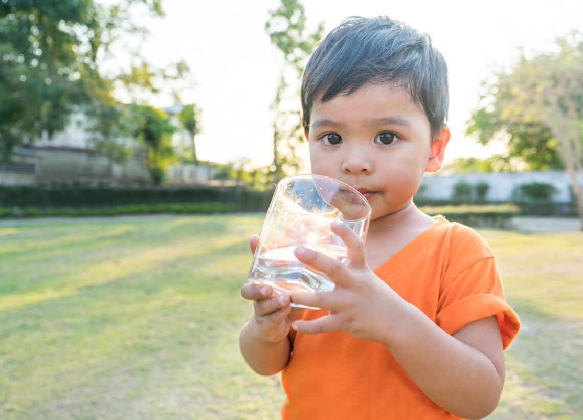 Kleiner Junge der Wasser aus einem Glas trinkt