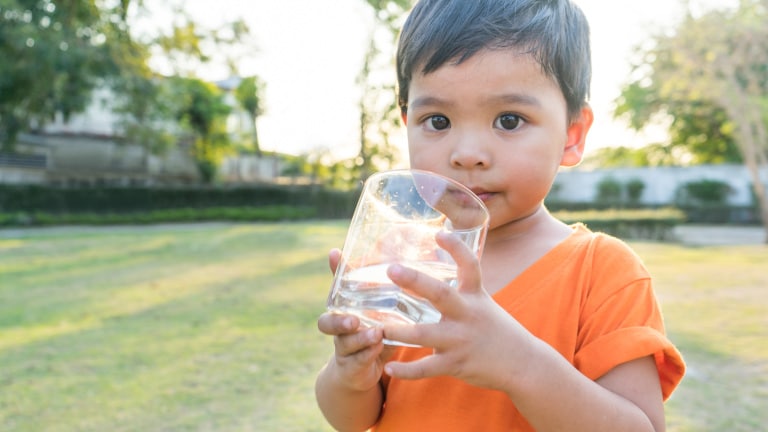 Kleiner Junge der Wasser aus einem Glas trinkt