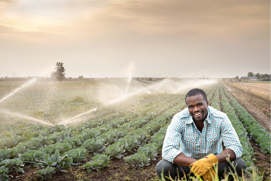 Smiling man kneeling in front of a field