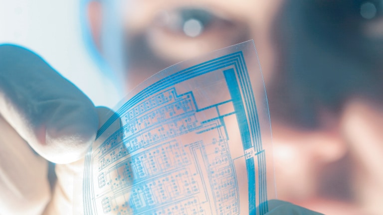 A man in a lab holds a plate in hand.