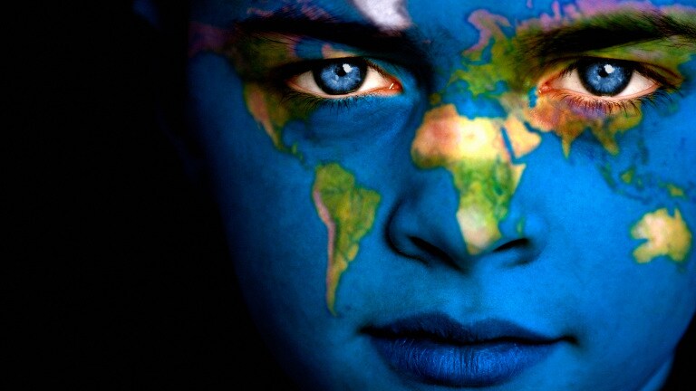 Portrait of a boy with the map of the world painted on his face.