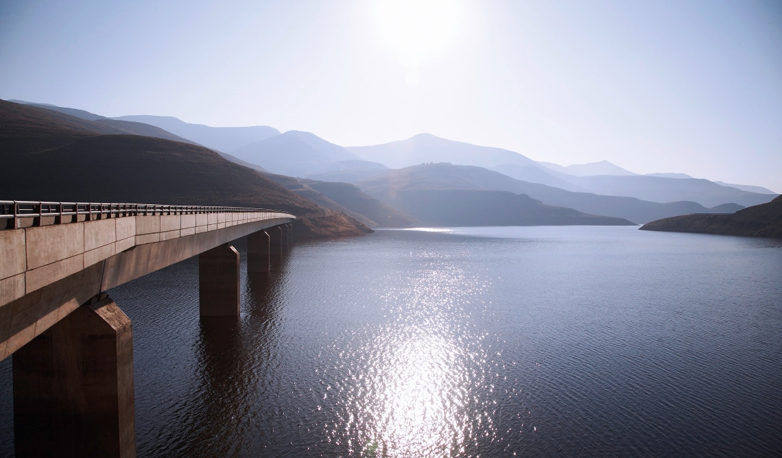 View of bridge going over Katse Dam with sun reflecting off water