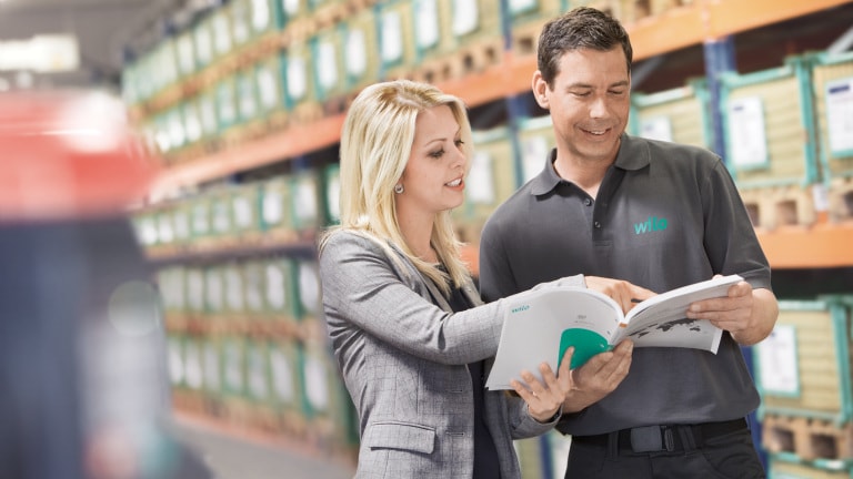 Alexandra Müller and Service technician looking into a price list/catalouge in the warehouseService Shooting 2014
